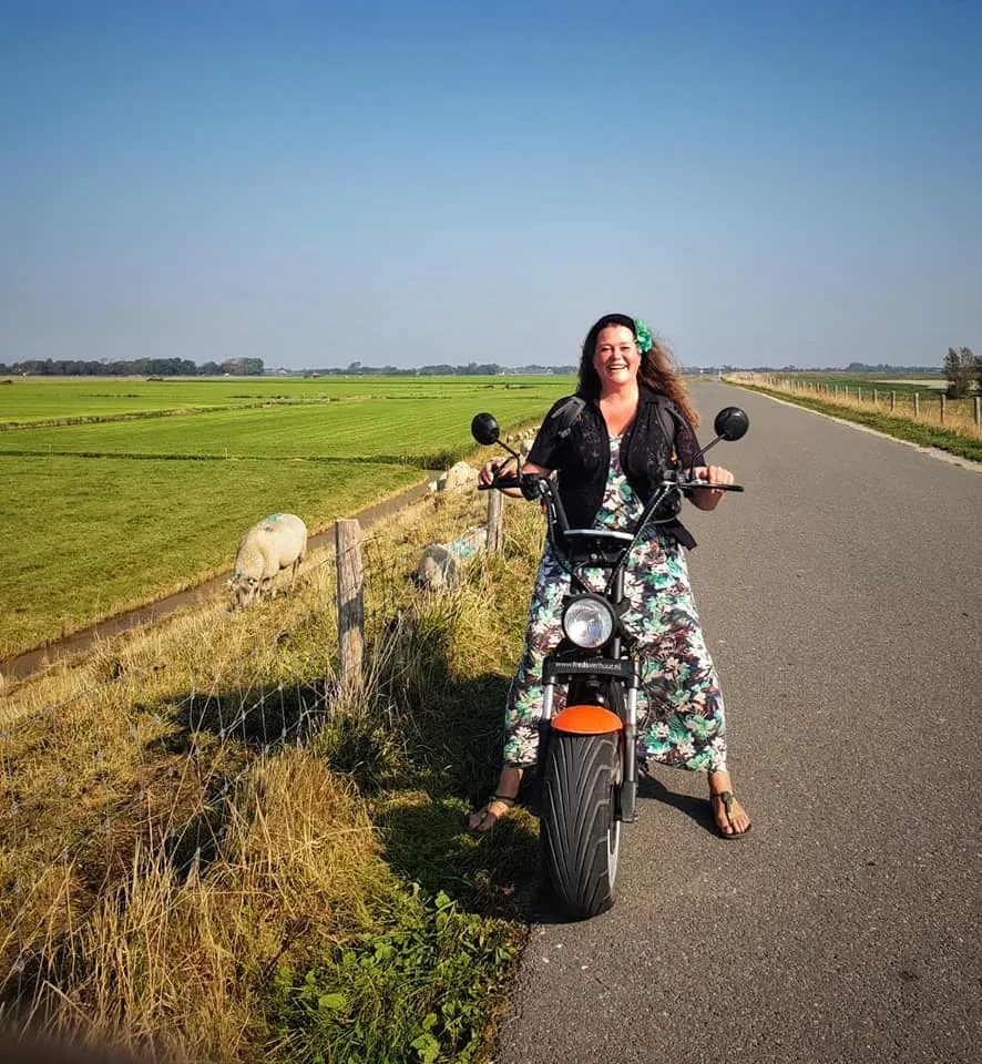 Frau auf einem E-Chopper auf einer Polderstraße bei Schagen